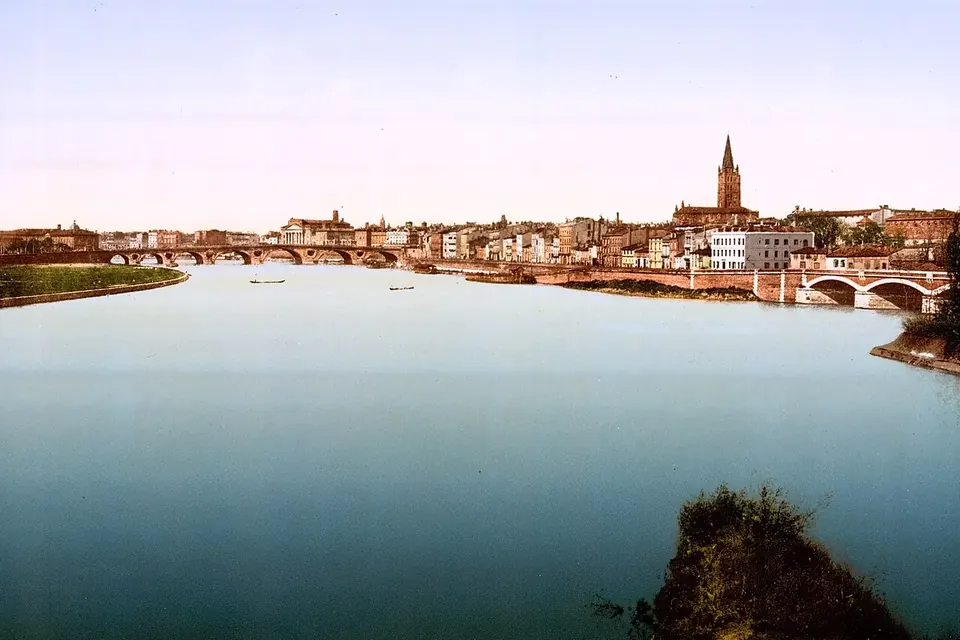 La Garonne à Toulouse vers 1895 : un large plan d'eau calme, la ville et son clocher à l'horizon, un pont sur la droite