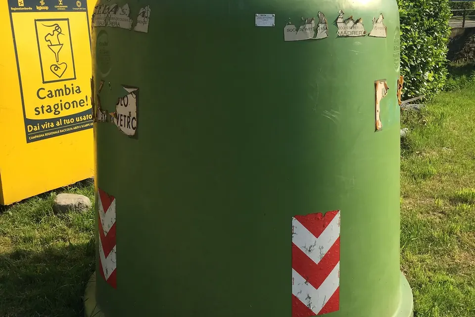 Conteneur de tri vert installé sur l'espace public, au bord d'une pelouse