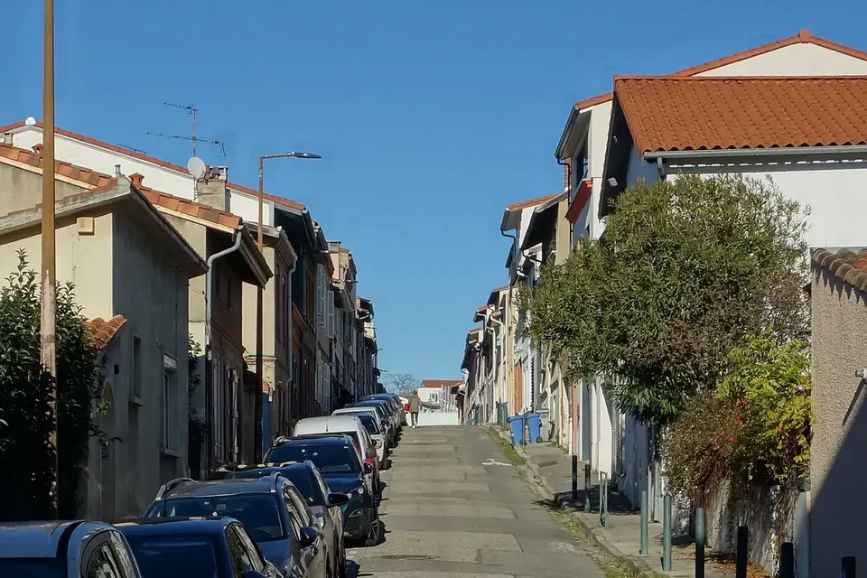 Rue résidentielle de Toulouse bordée de maisons et de petits immeubles aux toits de tuiles