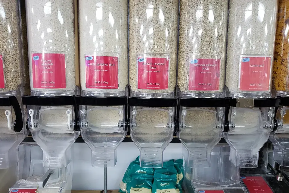 Rangée de distributeurs transparents remplis de différentes variétés de riz dans une épicerie sans emballage